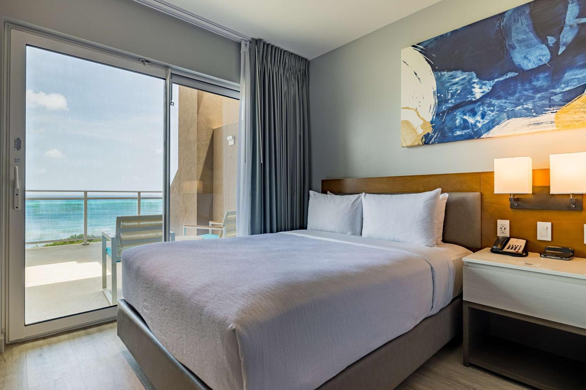 Suite de 1 dormitorio con cama extrangrande, balcón y vistas al mar